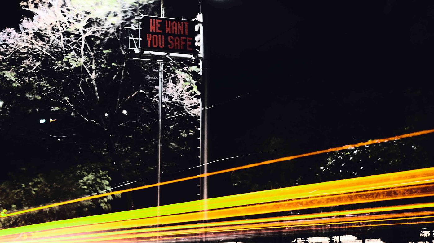 Light trails on a highway at night under a road safety sign